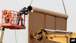 Crews work on a border wall prototype near the border with Tijuana, Mexico, Oct. 19, 2017, in San Diego, California.