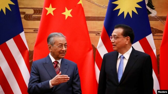 马来西亚总理马哈蒂尔（左）与中国总理李克强在北京人大会堂的签约仪式上。（2018年8月20日）