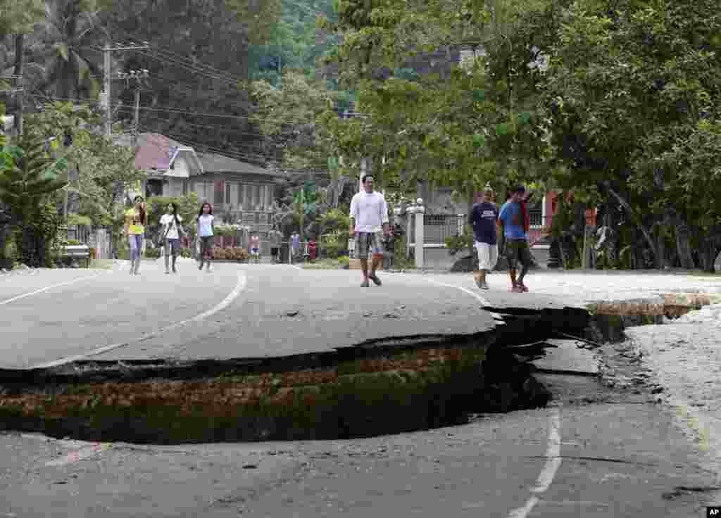 Residents walk on a damaged highway at Loboc township, Bohol province in central Philippines, Oct. 16, 2013.