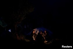 A Syrian family sits around a bonfire at a makeshift camp for refugees and migrants next to the Moria camp on the island of Lesbos, Greece, Nov. 30, 2017.