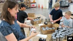 Una maestra y sus alumnos ponen etiquetas a latas de comida para ser distribuidas entre familias de bajos ingresos en Nuevo México.
