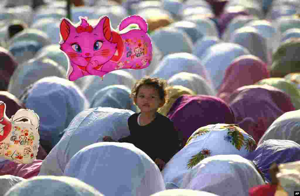 A Muslim girl holds a balloon during a morning prayer marking the Eid al-Adha holiday on a street in Jakarta, Indonesia, Oct. 15, 2013.