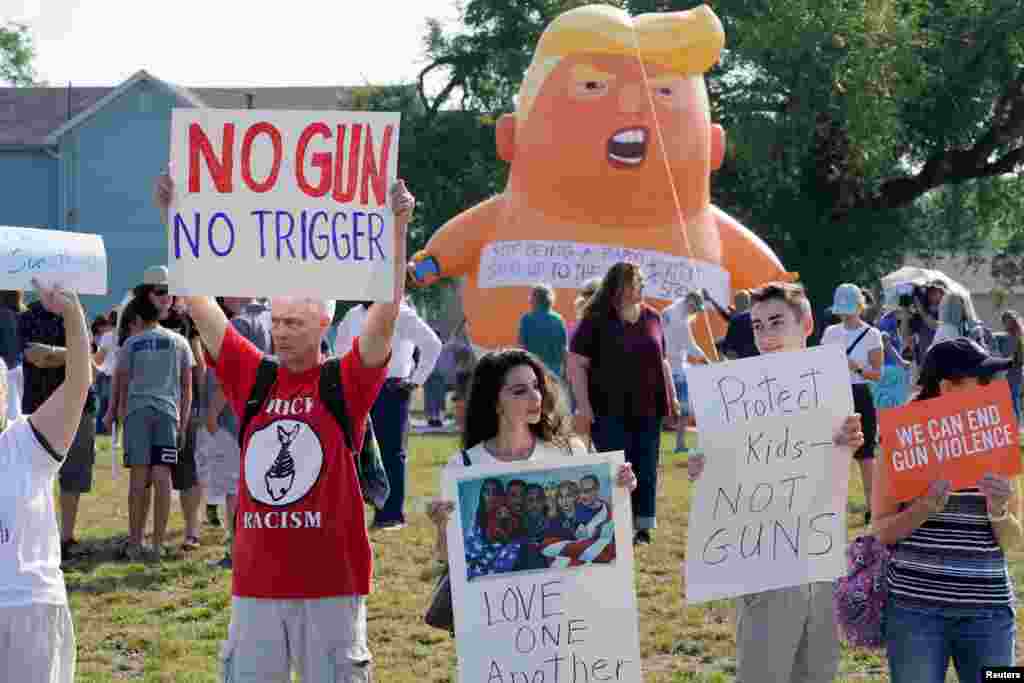 Protesters gather around a baby Trump balloon to demonstrate against gun violence and a visit from U.S. President Donald Trump following a mass shooting in Dayton, Ohio.
