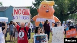 Protestors gather around a baby Trump balloon to voice their rally against gun violence and a visit from U.S. President Donald Trump following a mass shooting in Dayton, Ohio, U.S. August 7, 2019. 