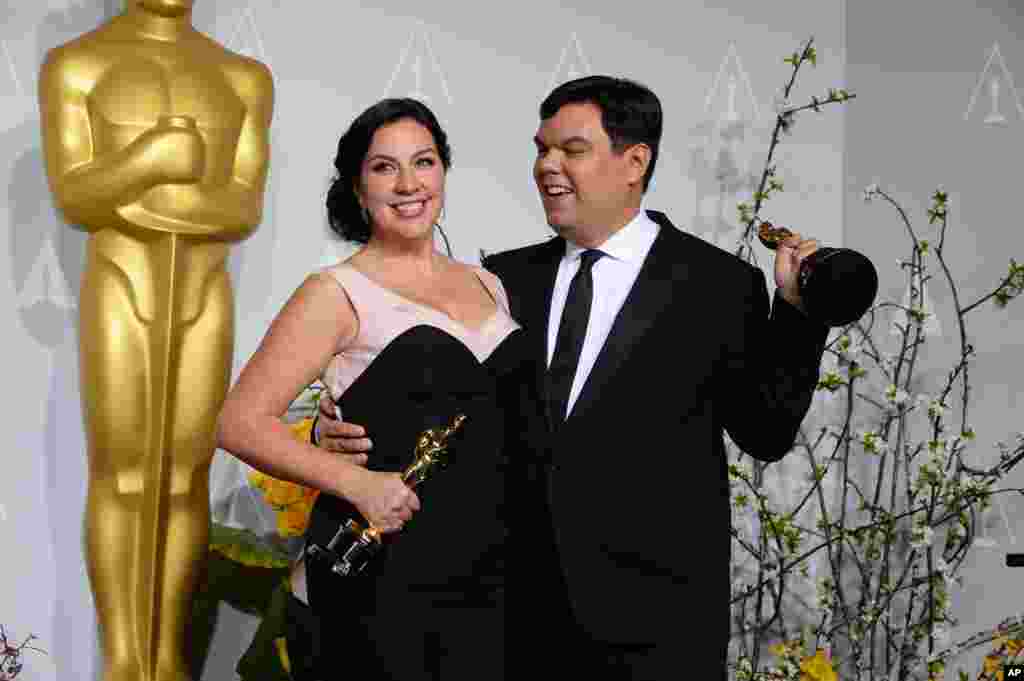 Kristen Anderson-Lopez, left, and Robert Lopez pose in the press room with their awards for best original song in a feature film for “Let It Go” from “Frozen” during the Oscars.