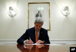 FILE - U.S. Secretary of State John Kerry signs a series of documents in Vienna, Austria, Jan. 16, 2016.