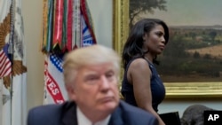 FILE - White House Director of communications for the Office of Public Liaison Omarosa Manigault, right, walks past President Donald Trump during a meeting on health care in the Roosevelt Room of the White House in Washington, March 13, 2017.