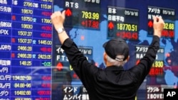 FILE - A man looks at an electronic stock indicator of a securities firm in Tokyo, Sept. 9, 2015.