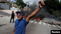 A demonstrator reacts near a burning barricade during a protest against government plans to privatize healthcare and education, in Tegucigalpa, Honduras, April 30, 2019. 