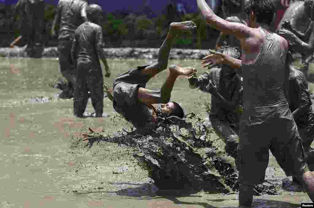 A boy is tossed in the mud during the Asar Pandhra festival in Pokhara valley, west of Nepal&#39;s capital Kathmandu, to mark the commencement of rice crop planting in paddy fields.