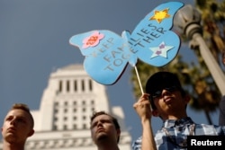 People hold signs to protest against U.S. President Donald Trump's executive order to detain children crossing the southern U.S. border and separating families outside of City Hall in Los Angeles, California, June 7, 2018.