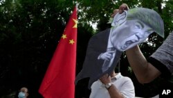 因美国制裁，支持中国的抗议者在美国驻香港领事馆外，手举美国总统唐纳德·特朗普的照片以示抗议。2020年8月8日图片。