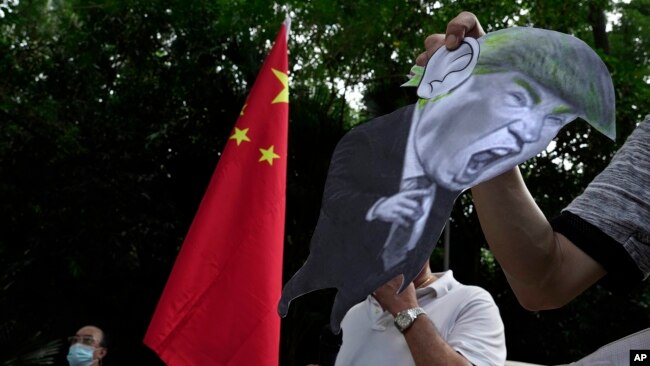 因美国制裁,支持中国的抗议者在美国驻香港领事馆外,手举美国总统唐纳德·特朗普的照片以示抗议。2020年8月8日图片。