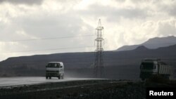 Vehicles drive past a high-voltage power line tower on a highway south of the Yemeni capital Sana'a February 26, 2010.