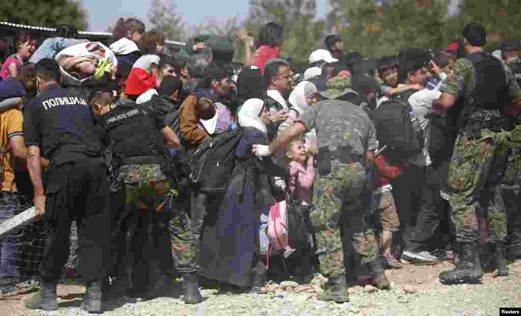 Macedonian soldiers and police officers try to maintain order while migrants board a train near Gevgelija, Sept. 7, 2015.