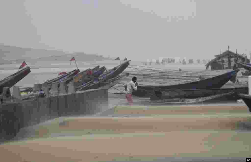 A fisherman walks near the anchored fishing boats as strong winds blow a day after a powerful cyclone pounded the Bay of Bengal coast in Gopalpur, Orissa, Oct. 13, 2014.