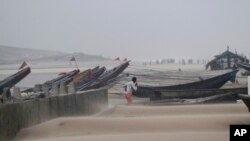 Seorang nelayan berjalan di dekat kapalnya yang sedang diikat di pelabuhan, saat angin kuat berhembus di pantai Gopalpur, wilayah Bengal, negara bagian Orissa, India (13/10).