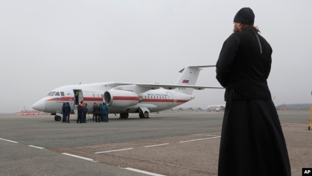Un sacerdote ortodoxo observa un avión que lleva cadáveres de las víctimas de la caida del avión de Metrojet en Egipto.