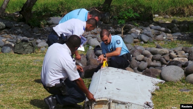 Gendarmes franceses examinan una pieza de los restos de un avión en la playa Saint-Andre, en la isla francesa La Reunión.