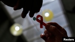Hình minh họa - Y tá đưa cho một người phụ nữ chiếc ruy-băng đỏ đánh dấu ngày Thế giới Phòng chống bệnh AIDS, 1/12/2014.