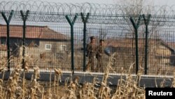 중국 단둥에서 바라본 북한 신의주에서 군인들이 철책을 순찰하고 있다.