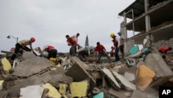 Para sukarelawan mencari penyintas di reruntuhan bangunan yang hancur karena gempa bumi di Pedernales, Ekuador (17/4). (AP/Dolores Ochoa)