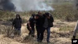 6일 가자지구 접경에서 팔레스타인 시위대가 이스라엘군의 발포로 다친 동료를 대피시키고 있다.