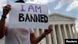 FILE - Mehrad Ansari of Iran holds a sign outside the U.S. Supreme Court after U.S. President Donald Trump's travel ban was upheld in Washington, June 26, 2018. 