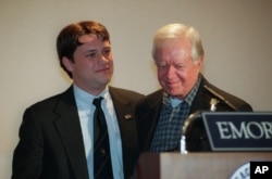 FILE - Former President Jimmy Carter, right, smiles after being introduced by grandson Jason Carter during a symposium on South Africa sponsored by the Peace Corps at Emory University in Atlanta.