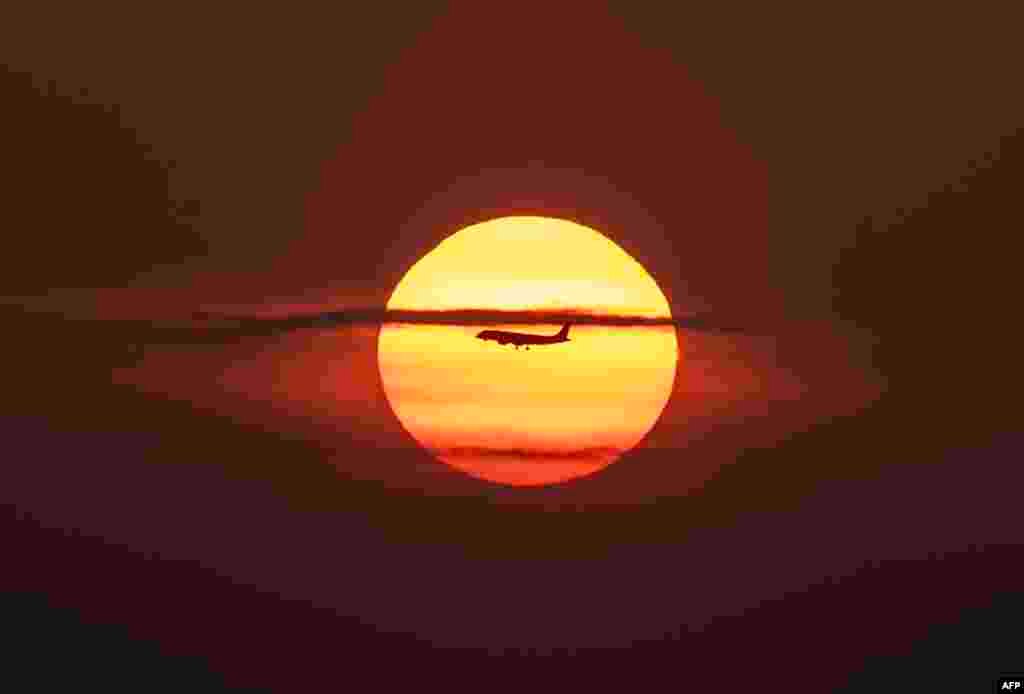 An airplane flies over Panama Bay, in Panama City during sunrise.