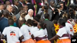 Pope Francis greets traditional dancers on his arrival at the airport in Nairobi, Kenya, Nov. 25, 2015.