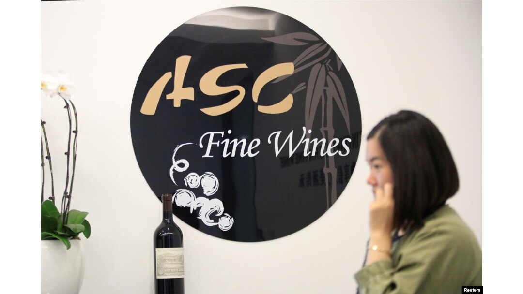 A woman walks past a sign of ASC Fine Wines at its headquarters in Shanghai, China, June 3, 2016.