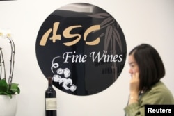 A woman walks past a sign of ASC Fine Wines at its headquarters in Shanghai, China, June 3, 2016.