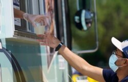 Penjual memberikan sampel minuman kepada seorang calon pembeli dari jendela truk makanannya di McKinney, Texas, Jumat, 18 Juni 2021. (AP)