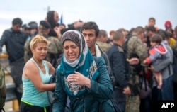 A migrant cries as she tries to break through the cordon of Macedonian police forces, while waiting to board a bus after crossing the Macedonian-Greek border near Gevgelija on Sept. 10, 2015.