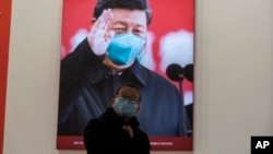 کرونا وائرس سے متعلق ایک نمائش میں شریک بچہ چین کے صدر ژی جن پنگ کی تصویر کو دیکھ رہا ہے ۔ فائل فوٹو اے پی