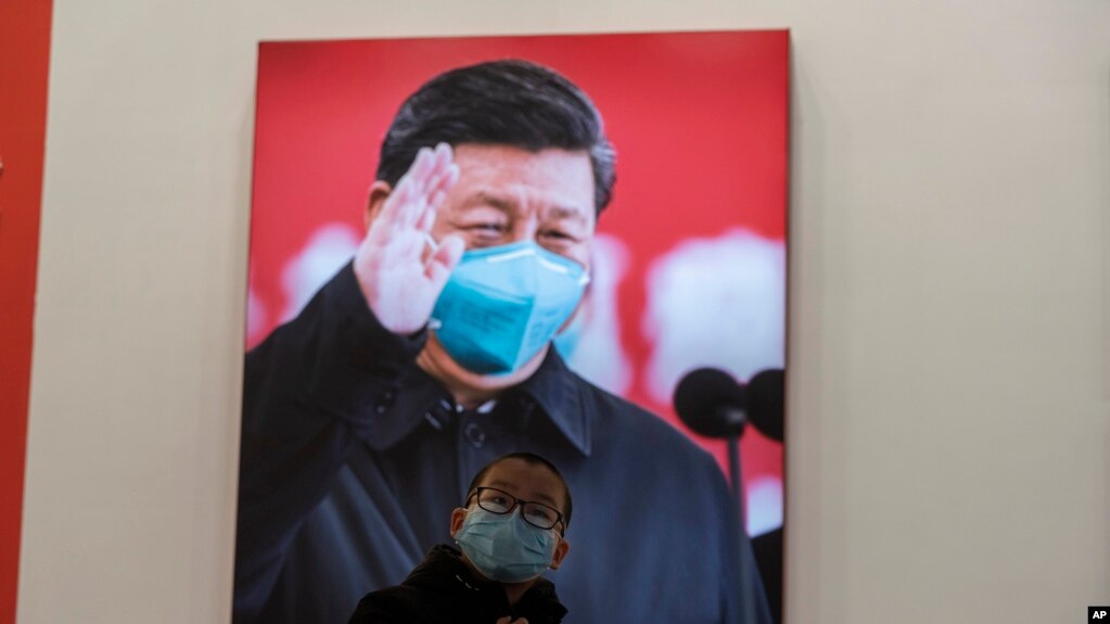 资料照片：2021年1月23日，武汉封城一周年当日，一名戴口罩儿童在武汉抗疫展览的习近平巨像前。（美联社Ng Han Guan拍摄图片）