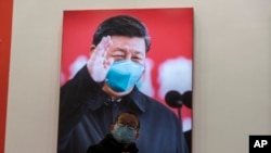资料照片：2021年1月23日，武汉封城一周年当日，一名戴口罩儿童在武汉抗疫展览的习近平巨像前。（美联社Ng Han Guan拍摄图片）