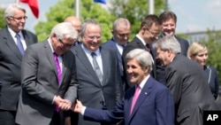 FILE - U.S. Secretary of State John Kerry, center, speaks with German Foreign Minister Frank-Walter Steinmeier, second left, and Greek Foreign Minister Nikos Kotzias, fourth left, during a group photo at NATO headquarters in Brussels.