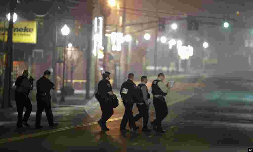 Police canvas the area as they investigate the scene where two police officers were shot, outside the Ferguson Police Department, March 12, 2015.