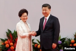FILE - Hong Kong Chief Executive Carrie Lam shakes hands with Chinese President Xi Jinping after she swore an oath of office on the 20th anniversary of the city's handover from British to Chinese rule, in Hong Kong, July 1, 2017.