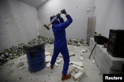 A customer wearing protective gear smashes old furniture with a hammer in an anger room in Beijing, China January 12, 2019. (REUTERS/Jason Lee)