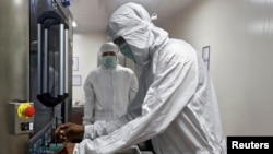 资料照片-印度血清研究所的实验室里，一名个人防护用品公司的员工正在从目测仪中取出阿斯利康的冠状病毒病(COVISHIELD)疫苗瓶子。（2020年11月30日）