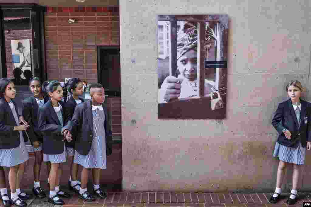 South African school children pause next to a portrait of the late South African anti-apartheid campaigner Winnie Madikizela-Mandela, ex-wife of African National Congress (ANC) leader Nelson Mandela, at her house in Soweto.