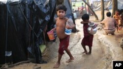 Pengungsi anak Rohingya berjalan ke tenda mereka setelah mengambil air minum di kamp darurat dekat kamp pengungsi Kutupalong di Cox's Bazar, Bangladesh, 3 Oktober 2017.