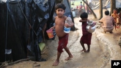 Rohingya children walk to their tents after fetching drinking water at a makeshift camp near Kutupalong refugee camp in Cox's Bazar, Bangladesh, Tuesday, Oct. 3, 2017. More than half a million Rohingya have fled from Myanmar to Bangladesh in just over a month, the largest refugee crisis to hit Asia in decades.