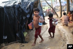 Rohingya children walk to their tents after fetching drinking water at a makeshift camp near Kutupalong refugee camp in Cox's Bazar, Bangladesh, Tuesday, Oct. 3, 2017.