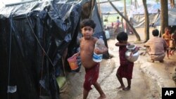 Rohingya children walk to their tents after fetching drinking water at a makeshift camp near Kutupalong refugee camp in Cox's Bazar, Bangladesh, Tuesday, Oct. 3, 2017. More than half a million Rohingya have fled from Myanmar to Bangladesh in just over a month, the largest refugee crisis to hit Asia in decades. 