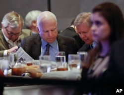 Sen. John McCain, R-Ariz., left, and Sen. Lindsey Graham, R-S.C., right, read the Wall Street Journal newspaper as they wait for President Donald Trump to speak to House and Senate GOP lawmakers at the annual policy retreat in Philadelphia, Jan. 26, 2017.