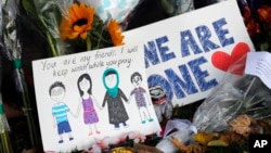 A message card is placed at a collection of flowers left at the Botanical Gardens in Christchurch, New Zealand, March 16, 2019. 